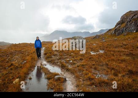 A person walking in Scottish countryside near the Allt Coire Rooill river in Torridon, Scotland Stock Photo