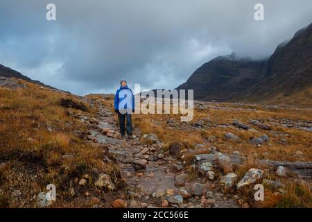 A person walking in Scottish countryside near the Allt Coire Rooill river in Torridon, Scotland Stock Photo