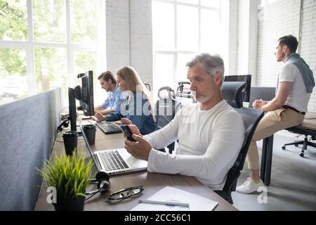 Man Working At Desk In Busy Creative Office. Stock Photo