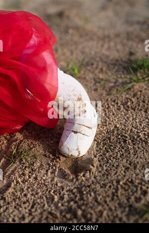 little child's foot in white tights stands on  yellow sand, dirt and sand on clothes