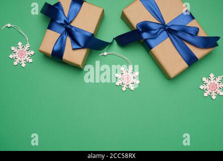 two rectangular boxes wrapped in brown paper and tied with a silk ribbon with a bow, gift on a green background, top view Stock Photo