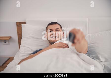 Handsome Caucasian man spending nice time in bedroom Stock Photo