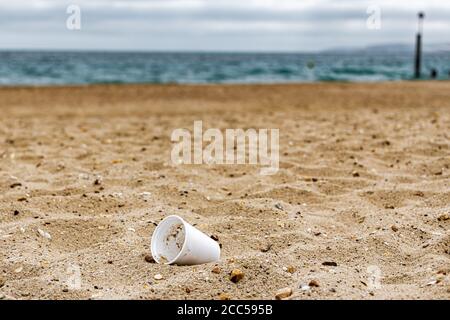 Plastic Pollution: Styrofoam Cup left by tourists on the beach. Cruise ship in background. Bournemouth, UK. Stock Photo