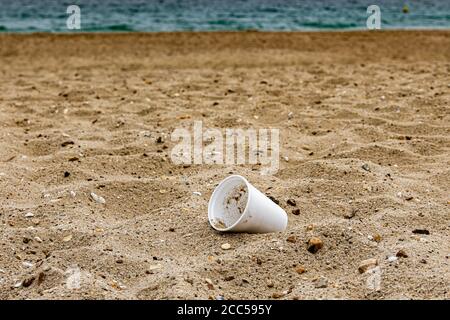 Plastic Pollution: Styrofoam Cup left by tourists on the beach. Cruise ship in background. Bournemouth, UK. Stock Photo
