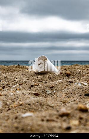 Plastic Pollution: Styrofoam Cup left by tourists on the beach. Cruise ship in background. Bournemouth, UK. Stock Photo