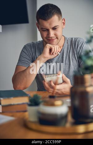 Interested young man sitting at home with notebook Stock Photo