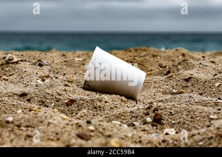 Plastic Pollution: Styrofoam Cup left by tourists on the beach. Cruise ship in background. Bournemouth, UK. Stock Photo