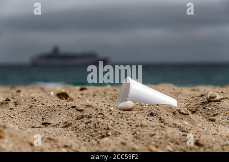 Plastic Pollution: Styrofoam Cup left by tourists on the beach. Cruise ship in background. Bournemouth, UK. Stock Photo