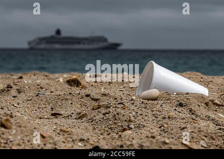 Plastic Pollution: Styrofoam Cup left by tourists on the beach. Cruise ship in background. Bournemouth, UK. Stock Photo