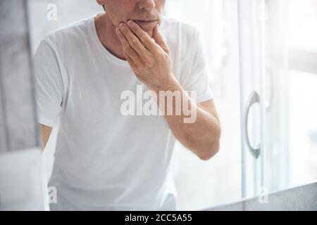 Serious adult Caucasian man examining his skin Stock Photo