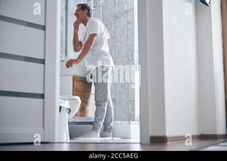 Man in home clothing standing at the wash basin Stock Photo