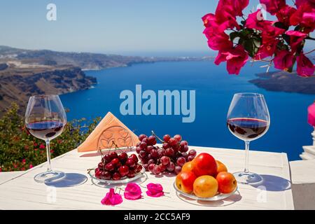 Two glasses of red wine and fruit on the background of the sea in Greece Stock Photo