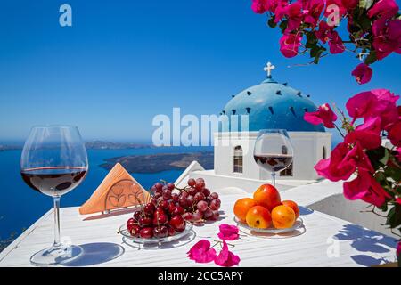 Two glasses of red wine and fruit on the background of the sea in Greece Stock Photo