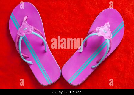 pink and turquoise flip flops on orange coloured towel Stock Photo