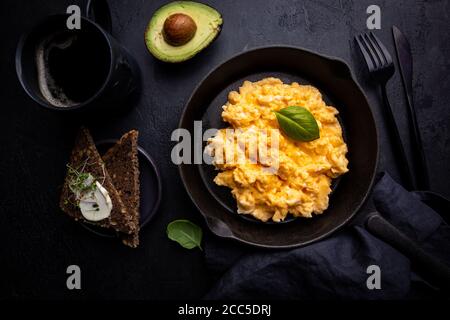 Fresh cooked scrambled eggs in a cast iron skillet on black background, top view Stock Photo