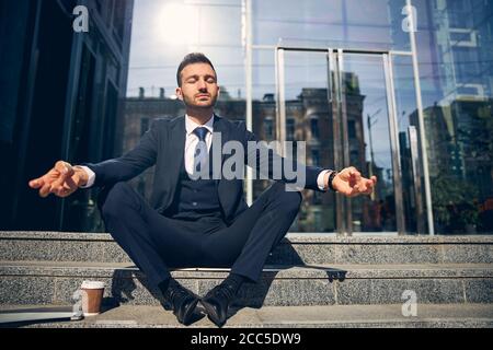 Young brunette male meditating outside near office Stock Photo