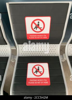 Please do not sit here sign on bench at Vilnius airport. Passengers have to keep 1-2 meters social distancing to protect from corona virus spreading.