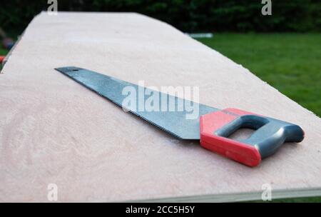 Sharp metal saw lying on a piece of wood ready to be cut for construction Stock Photo