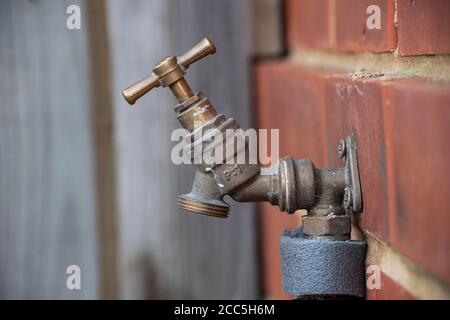 Isolated outdoor tap on the side of a brick house, ready for a hose attachment Stock Photo