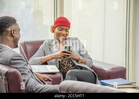 Young African business lady using her mobile phone and smiling Stock Photo