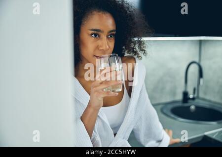 Thoughtful dark-haired woman leaning on the countertop Stock Photo