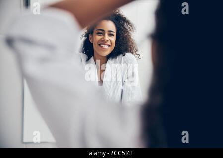 Cheerful female in a bathrobe standing in the bathroom Stock Photo