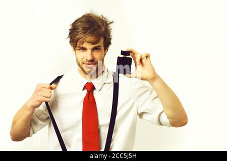 Bearded man, short beard. Caucasian stylish smiling man posing with perfume in shirt and suspenders in studio isolated on white background Stock Photo