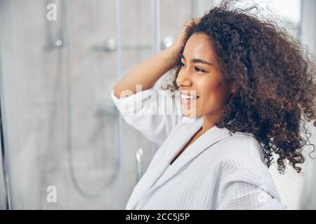 Smiling female standing before the bathroom mirror Stock Photo
