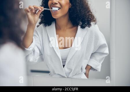 Female cleaning her teeth with a toothbrush Stock Photo