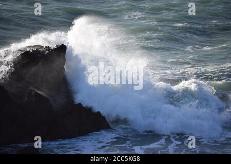 Sunlit wave breaking on rock Stock Photo