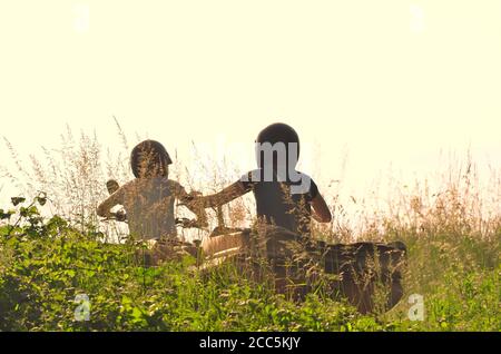 Rear view of young people driving a quad bike on a sunny day. Stock Photo