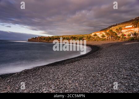 La Caleta of Interian pebbles beach, with sunset sunlight and grey clouds, long exposure, Tenerife, Canary islands, Spain Stock Photo