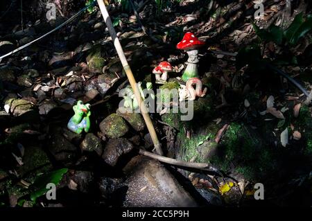 Garden ornaments over some rocks and close to a stream of crystal clear water under tree shade found inside O Contemplario farm. Stock Photo