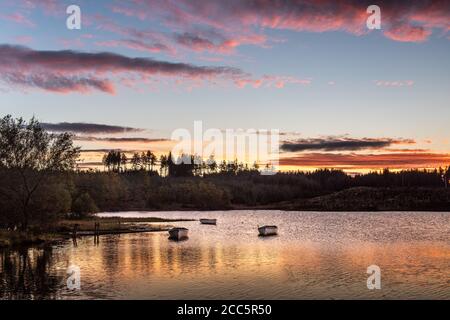 Fishing boats on Loch Rusky at sunrise, a small freshwater loch near Callander in the Scottish Highlands. Stock Photo