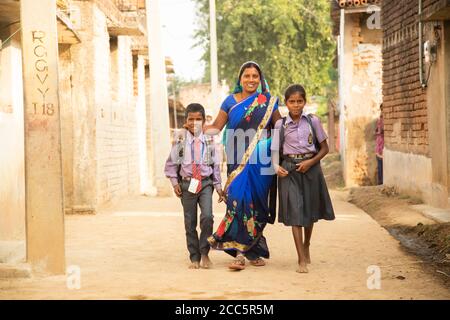 A mother walks her two children, wearing school uniforms, to school in a village in Bihar, India, South Asia. Stock Photo