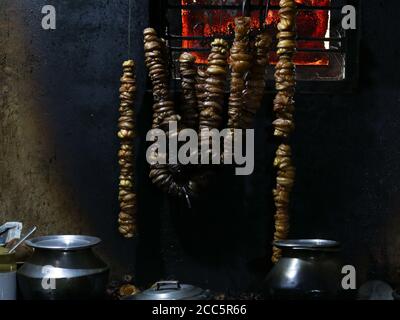 Chain of cut brindle berry or Malabar tamarind hung for drying at fire place in a village home. Scientifically known as Garcinia gummi-gutta,a tropica Stock Photo