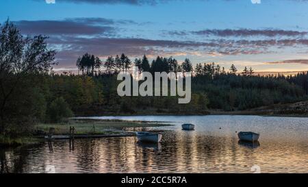 Fishing boats on Loch Rusky at sunrise, a small freshwater loch near Callander in the Scottish Highlands. Stock Photo