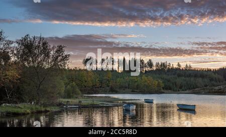 Fishing boats on Loch Rusky at sunrise, a small freshwater loch near Callander in the Scottish Highlands. Stock Photo