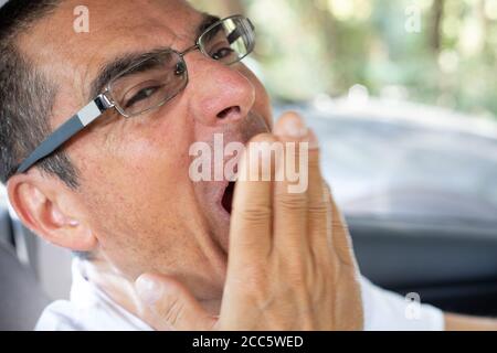 Man tired yawning with his hand in front of the mouth Stock Photo