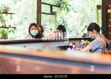 Woman barista with protection face mask making coffee for customer in cafe Stock Photo