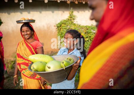 A woman and her daughter carry freshly harvested gourds and vegetables from their garden in a rural village in Bihar, India, South Asia. Stock Photo