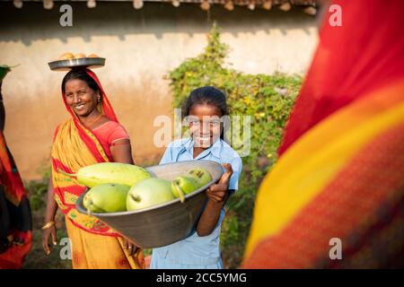 A woman and her daughter carry freshly harvested gourds and vegetables from their garden in a rural village in Bihar, India, South Asia. Stock Photo