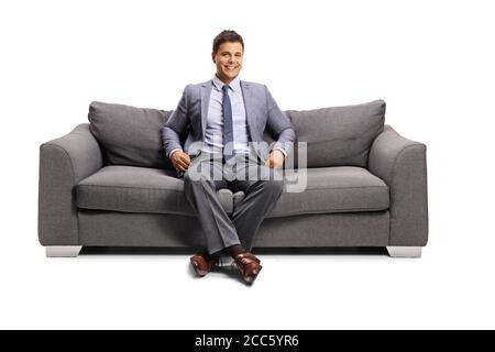 Man in elegant clothes sitting on a sofa and smiling isolated on white background Stock Photo