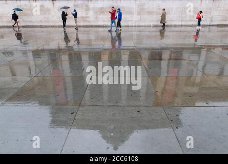 The National Gallery is seen reflected in wet paving during rainfall in Trafalgar Square, London, as many parts of the UK experience wet weather ahead of the arrival of Storm Ellen, which is forecast to bring strong winds. Stock Photo