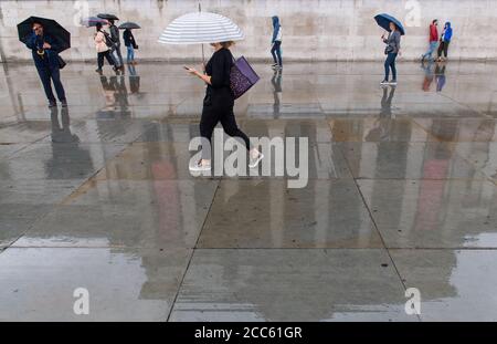 The National Gallery is seen reflected in wet paving during rainfall in Trafalgar Square, London, as many parts of the UK experience wet weather ahead of the arrival of Storm Ellen, which is forecast to bring strong winds. Stock Photo