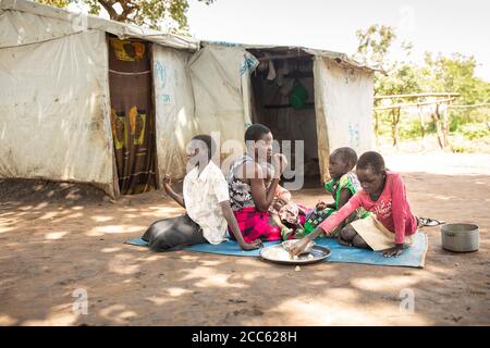 A family from South Sudan shares a meal together in Palabek Refugee Settlement in northern Uganda, East Africa. Stock Photo