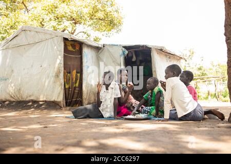 A family from South Sudan shares a meal together in Palabek Refugee Settlement in northern Uganda, East Africa. Stock Photo