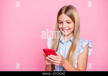 Portrait of positive blogger kid girl use smart phone enjoy social media news subscribe comment repost wear denim jeans shirt isolated over pastel Stock Photo