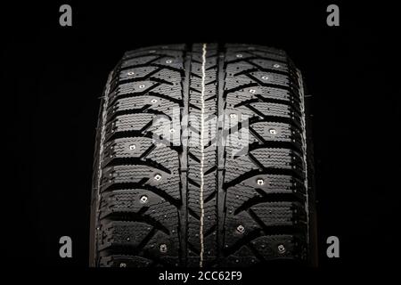 new winter studded tire close-up on a black background, front view Stock Photo