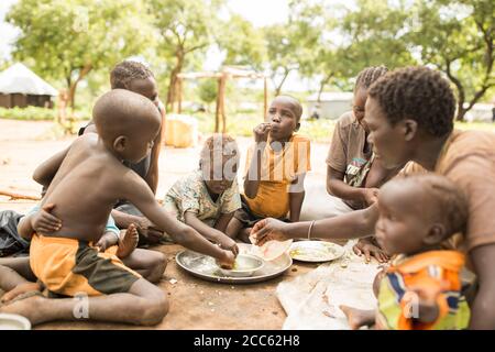 A family from South Sudan shares a meal together in Palabek Refugee Settlement in northern Uganda, East Africa. Stock Photo